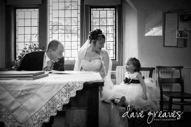 Bride and Groom signing the register shar a joke with the flower girl