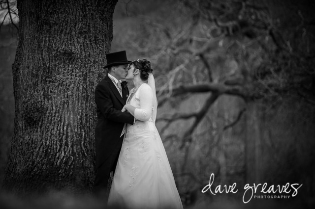 Bride and Groom embrace standing under a tree