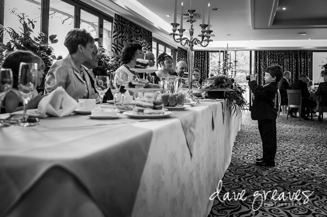 Young wedding guest takes a picture of the top table at wedding reception